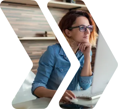 A person resting their head on their hand at a desk looking at a screen